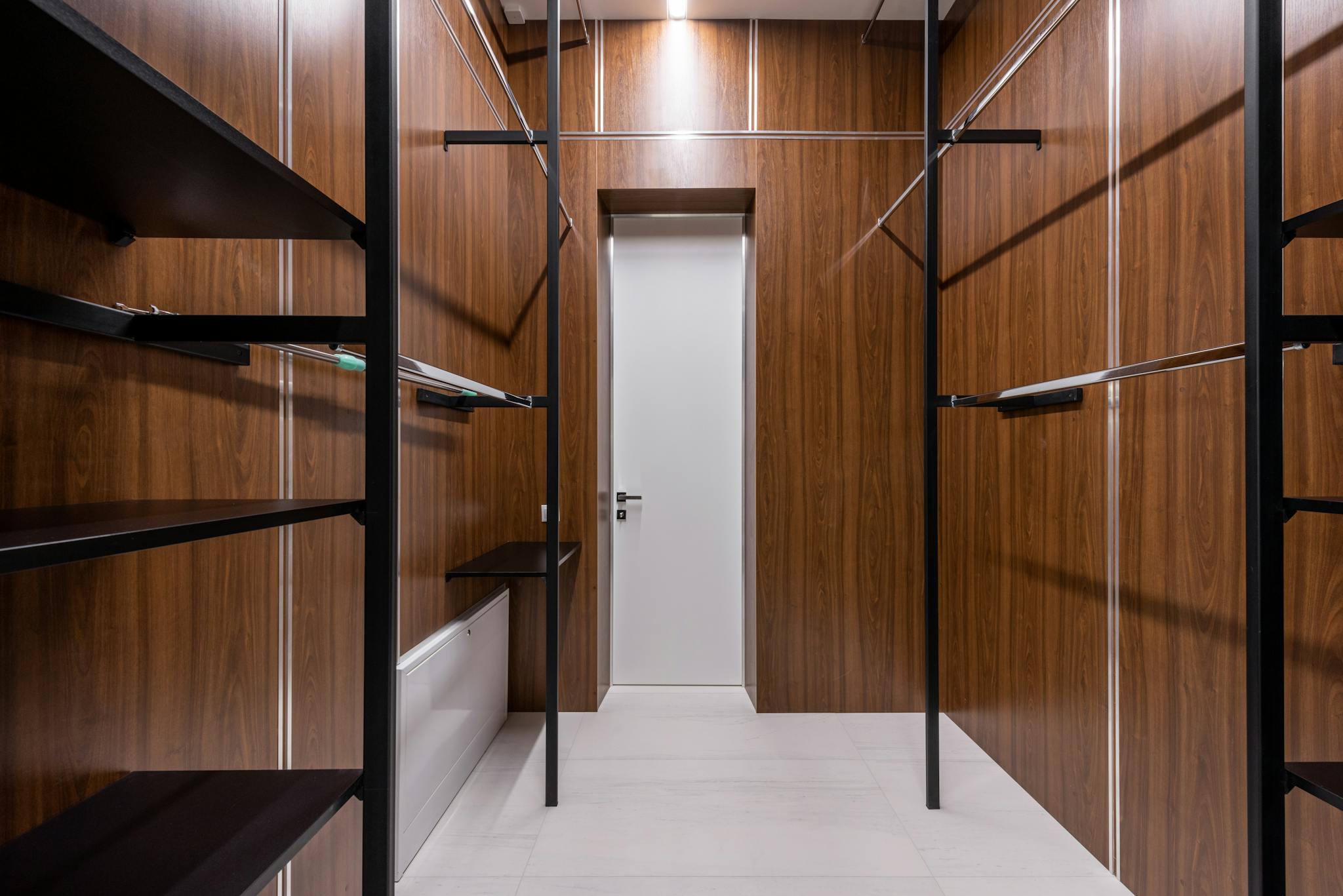 A sleek and modern walk-in closet with wood paneling and black accents.